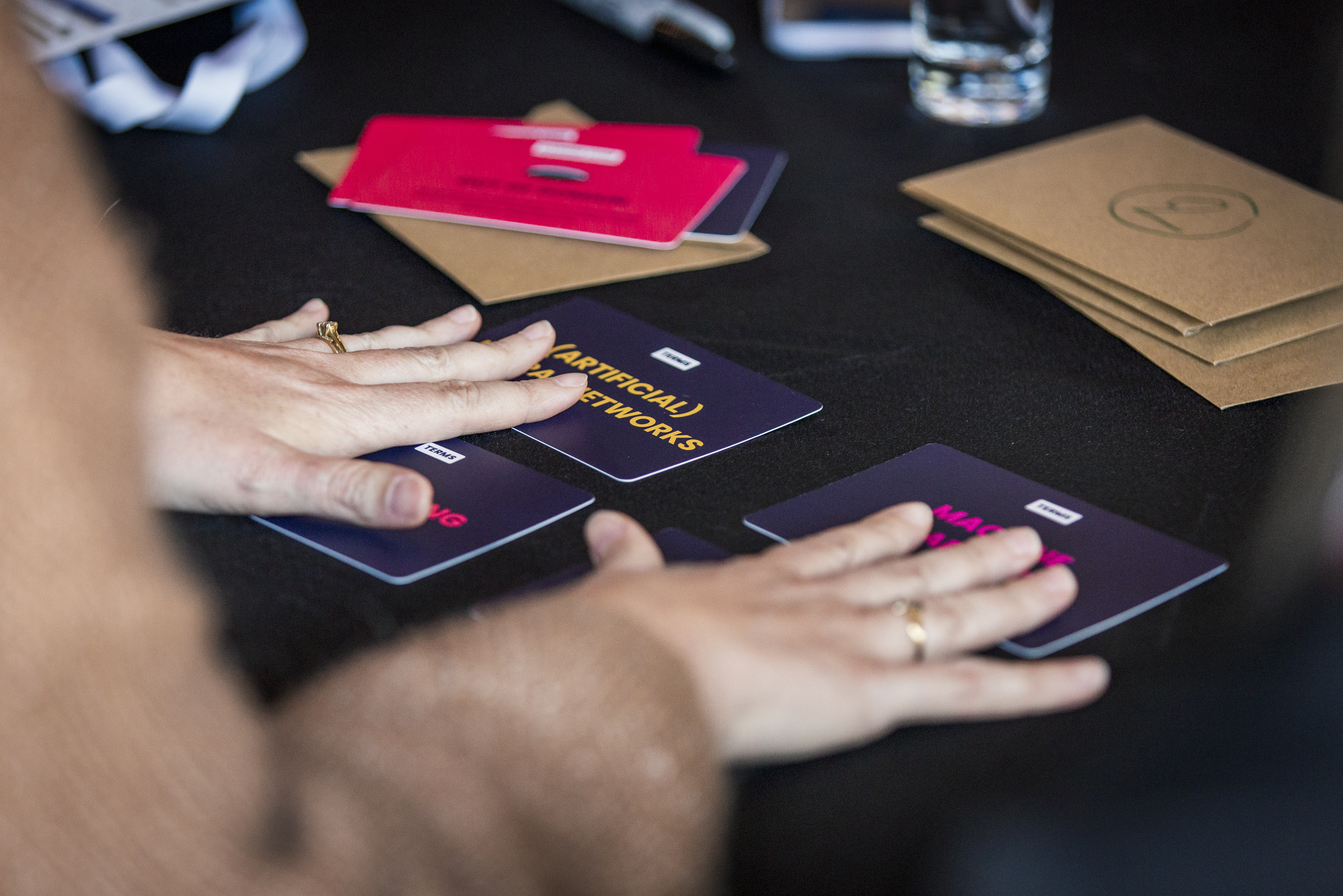 Photo of hands of a participant manipulating the vocabulary cards from the AI Tinkerer's Cards
